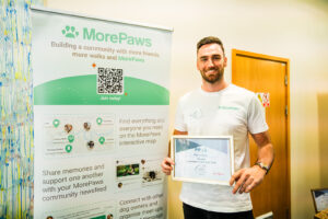 MorePaws Founder at the 2024 Business of Pets Conference standing in front of a branded promotional banner.